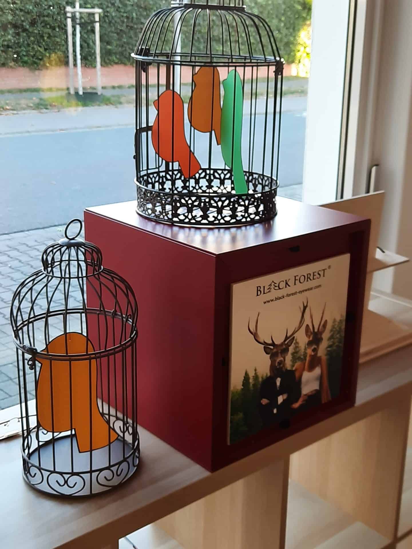 Zwei dekorative Vogelkäfige mit bunten Papageienfiguren
