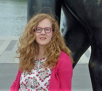 Frau mit rotem Haar vor Skulptur
