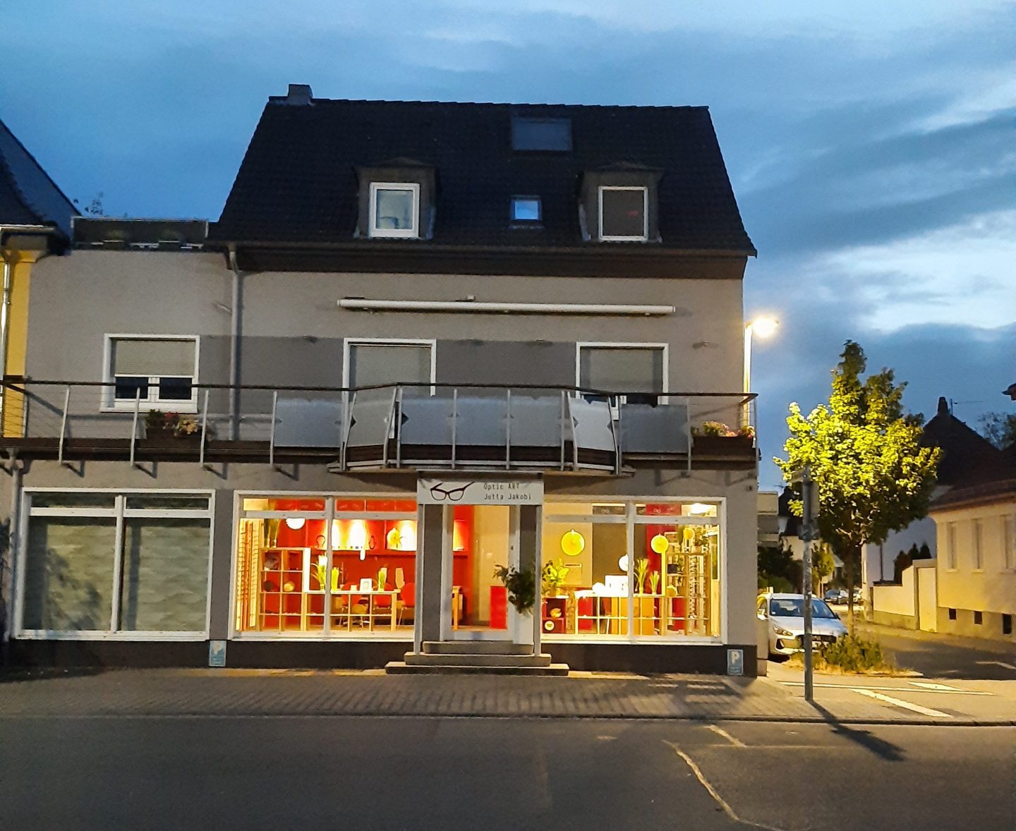 Geschäftsgebäude bei Abenddämmerung mit beleuchtetem Schaufenster.