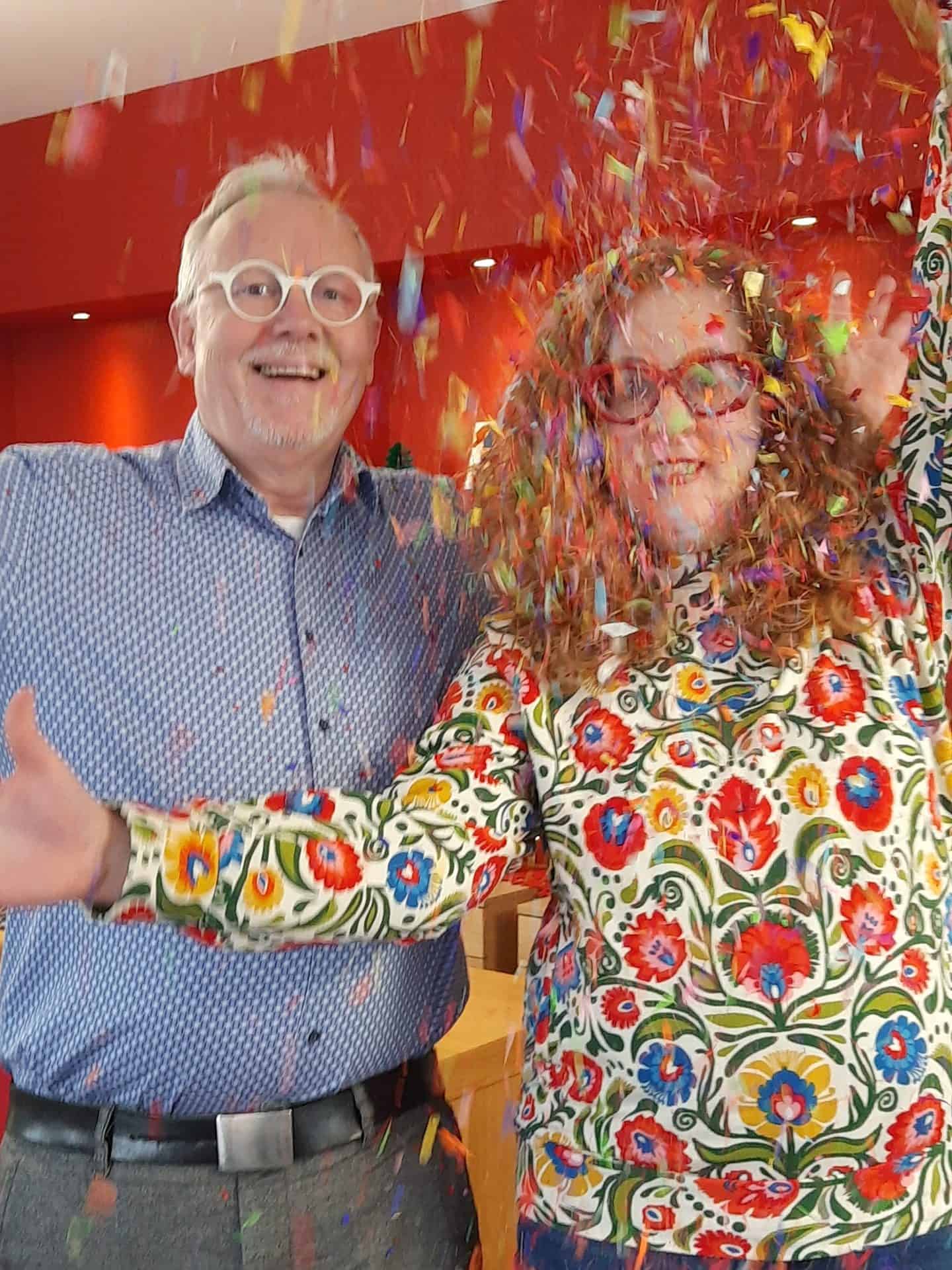 Zwei Personen werfen buntes Konfetti.