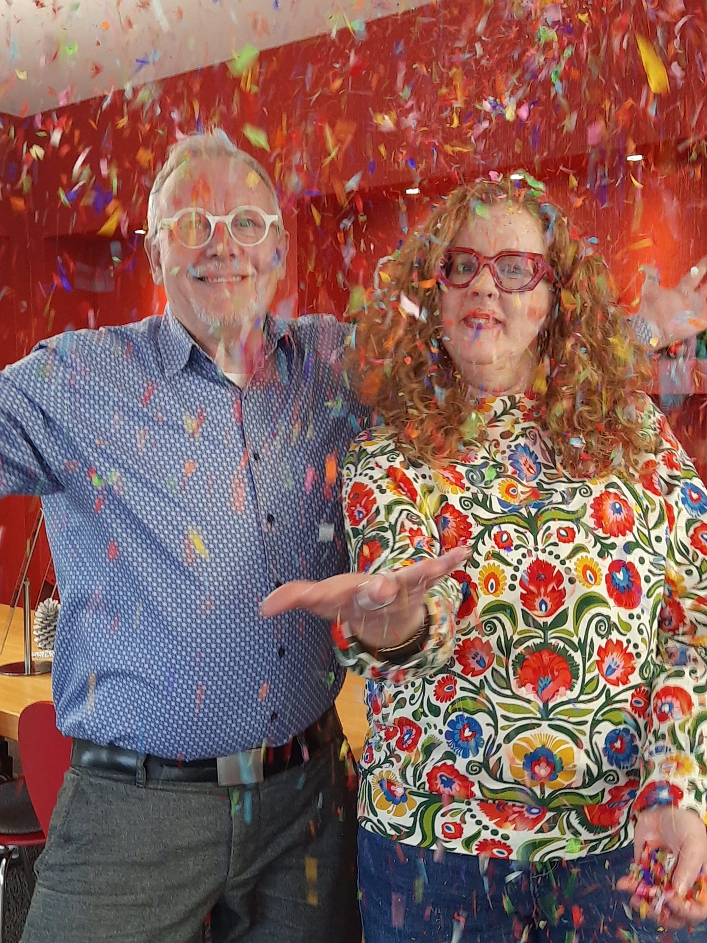 Zwei Personen feiern mit buntem Konfetti.