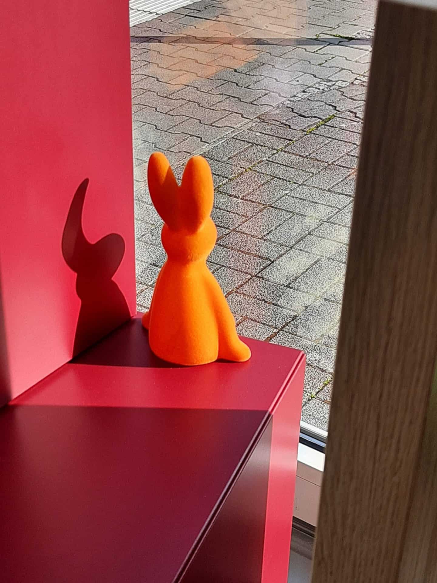 Orange Kaninchenfigur mit Schatten auf Regal